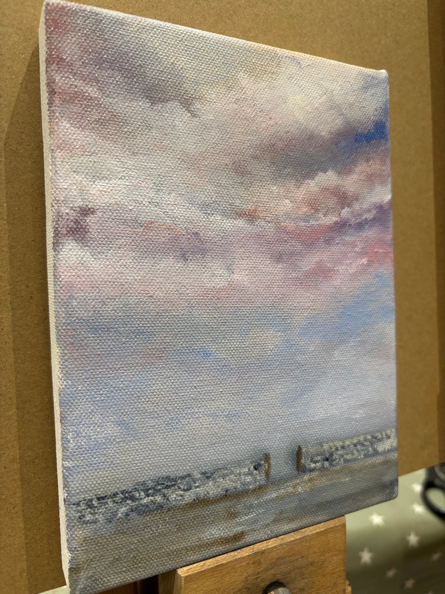 Small painting of a purple and pink sky with a stone wall across the bottom and a gate.