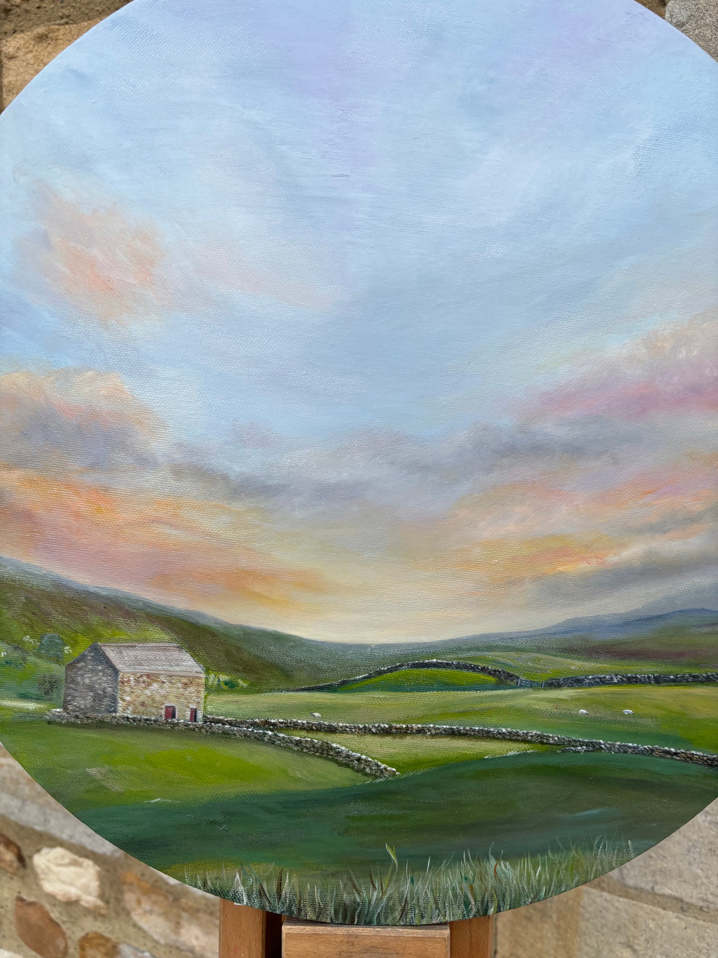 Painting of a landscape with a house and rolling hills under a colorful sky.