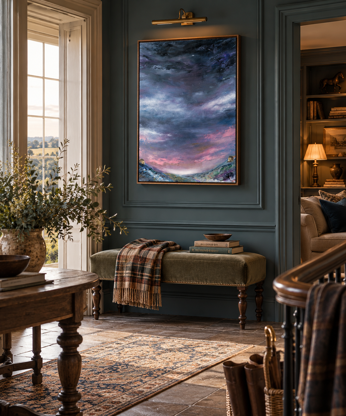 A framed vertical landscape painting of a stormy sky over mountains in purple, blue, and pink tones, displayed on a dark teal wall in a beautifully styled home interior with a bench, rug, and wooden furniture.