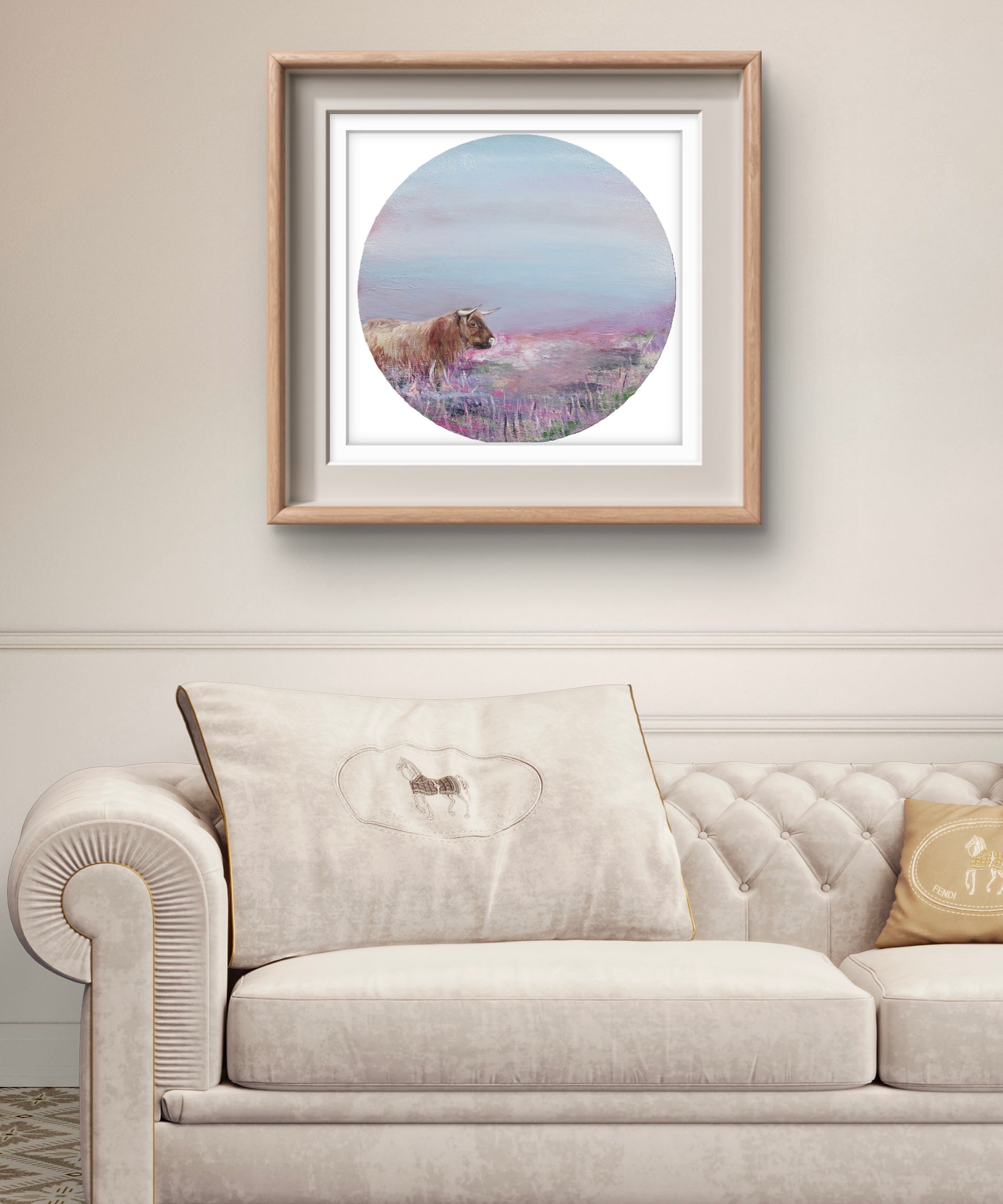 Framed artwork of a Highland Cow in a field of heather above a beige sofa.