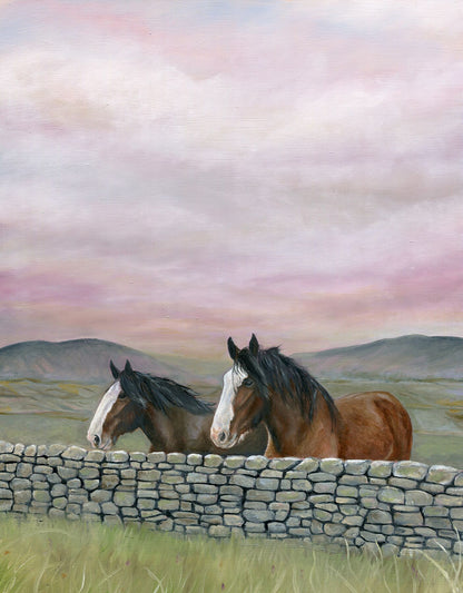 Two horses behind a stone wall with a scenic landscape and pink sky.