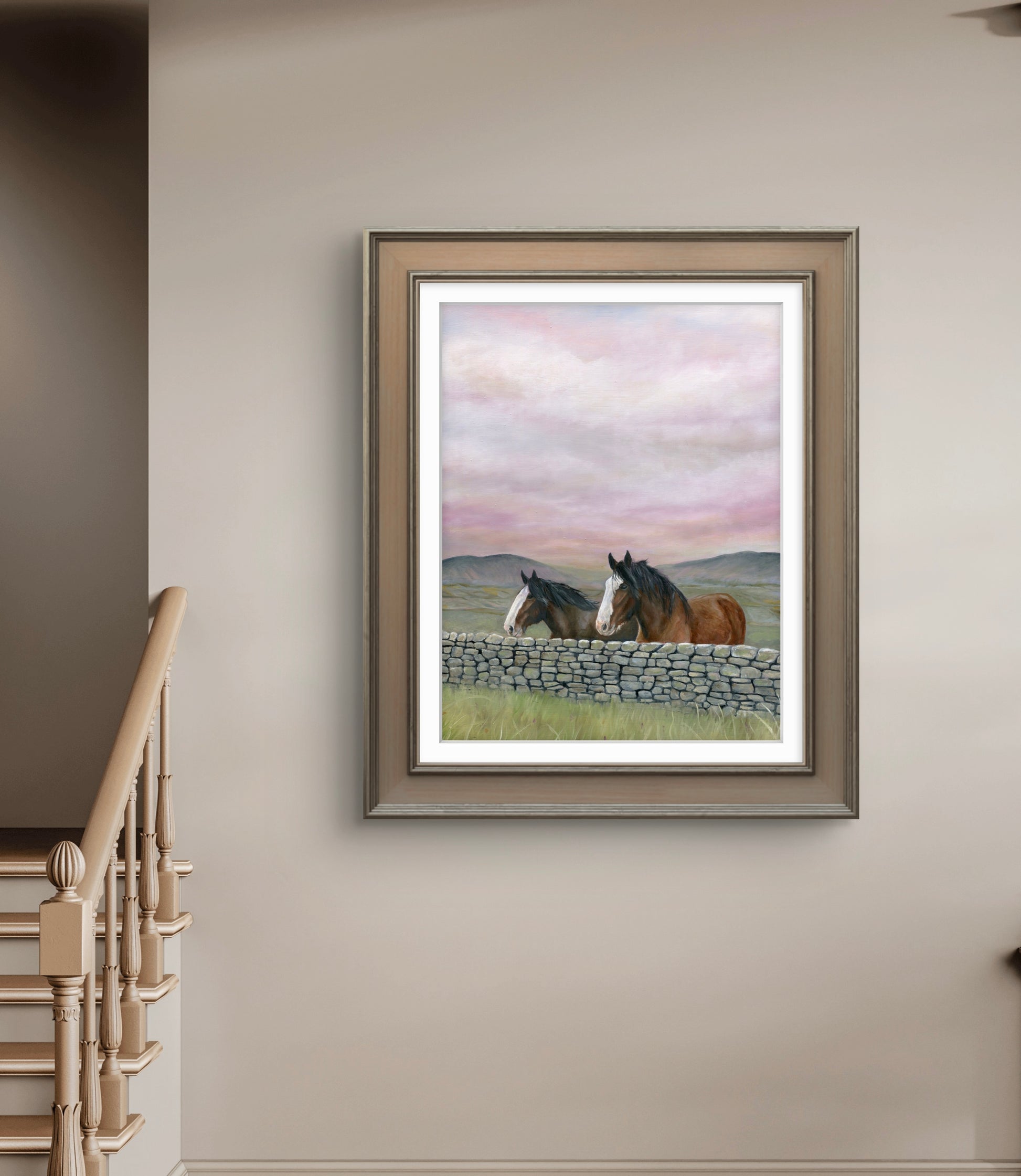 Framed artwork of two horses by a stone wall on a wall above a staircase.