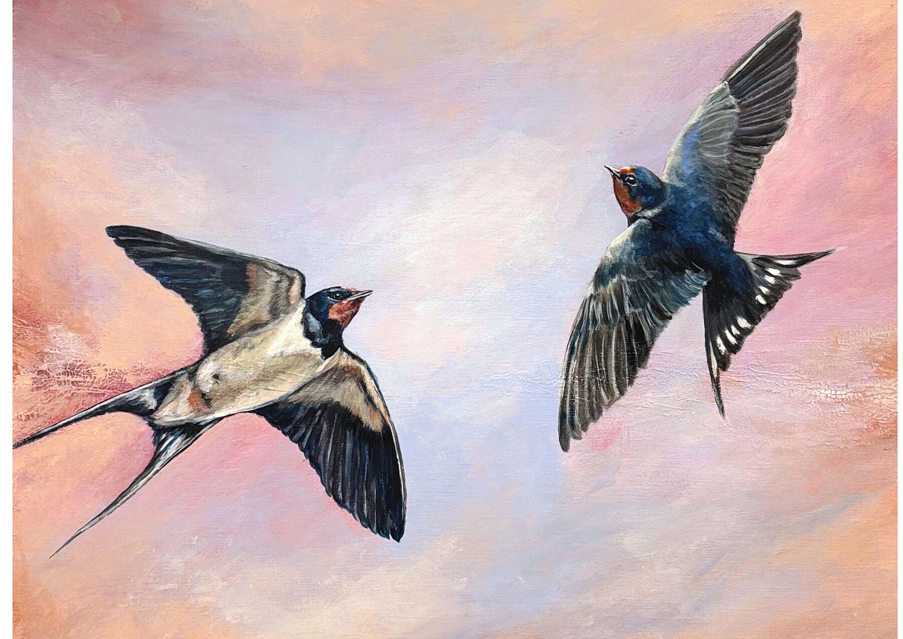 Two swallows flying against a pastel sky with pink and blue hues