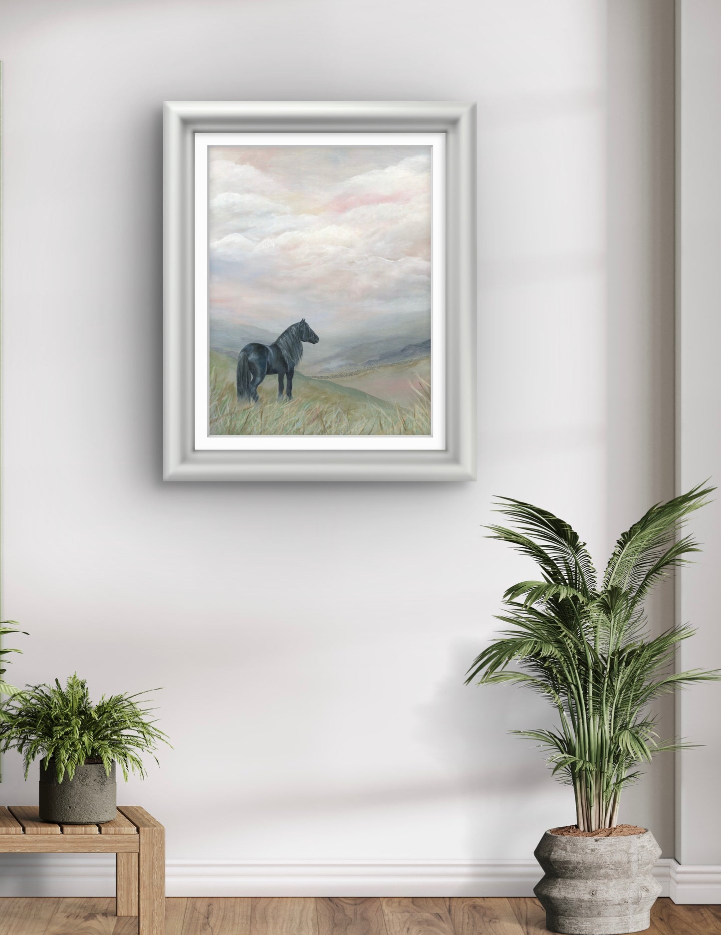 Framed artwork of a horse on a hillside in a room with plants and a wooden bench.