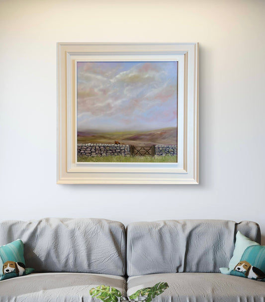 Framed landscape painting above a sofa with decorative pillows.