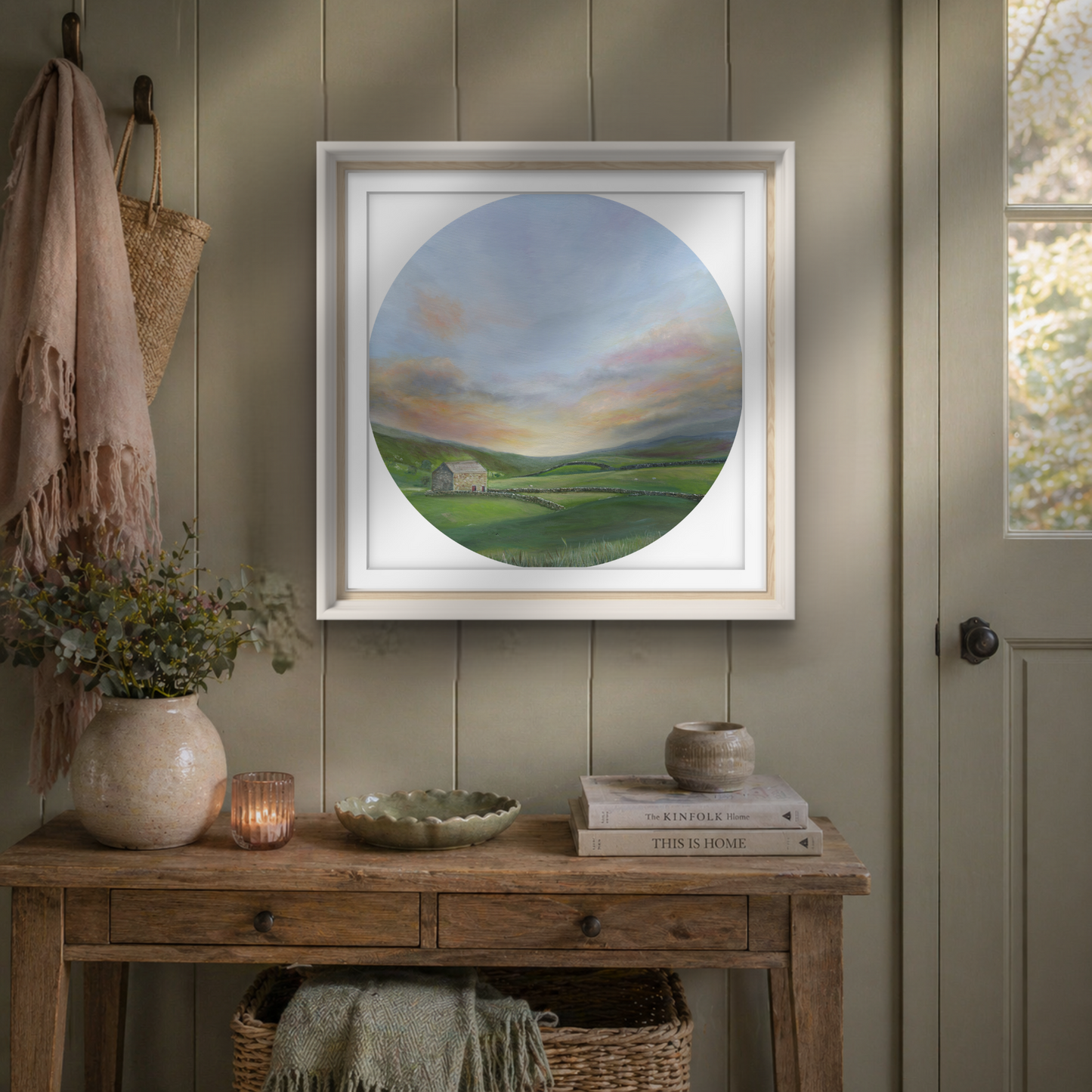 Landscape art print framed in a hallway above a wooden console
