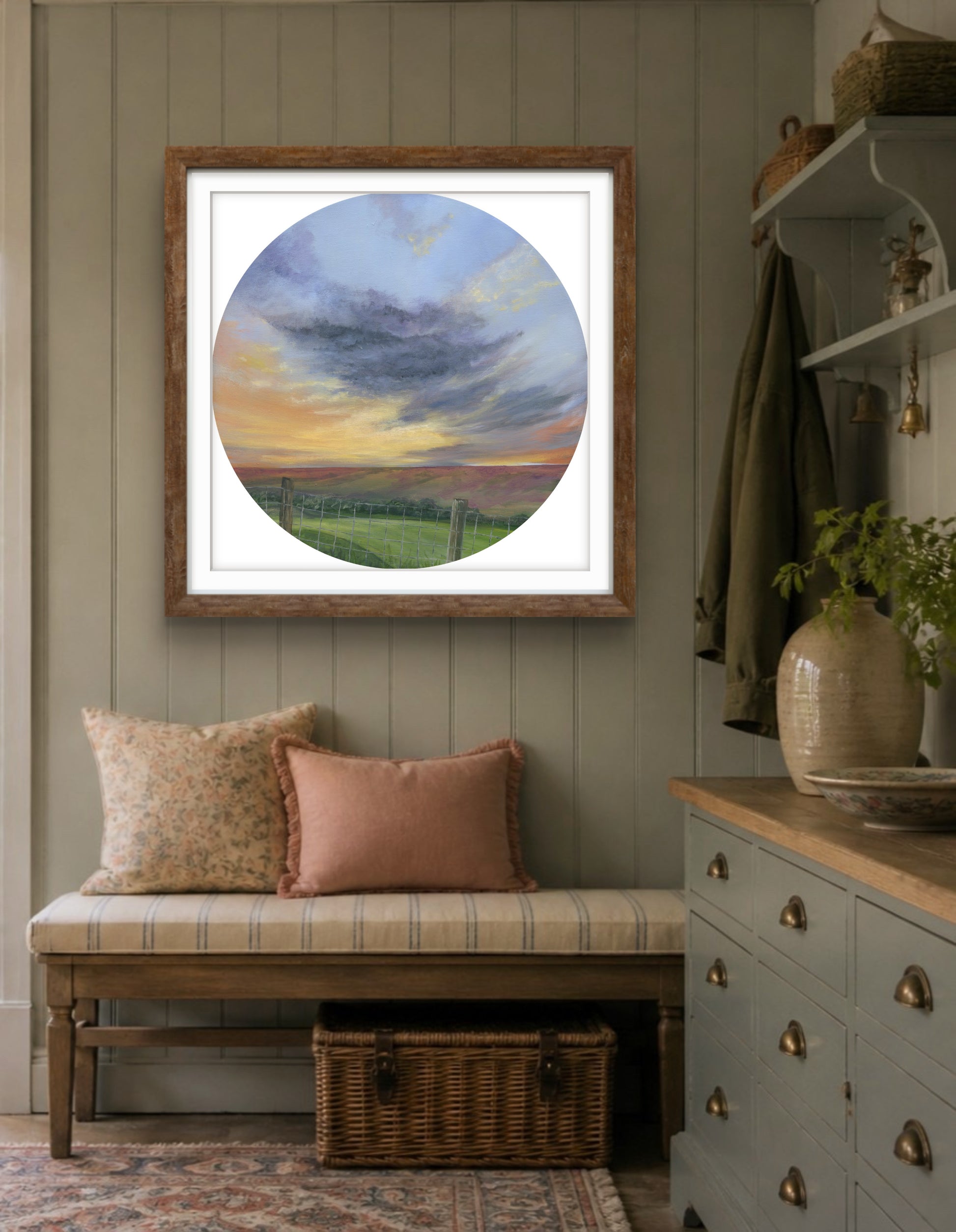 Framed artwork of a cloudy sky in a hallway with dresser and fabric bench