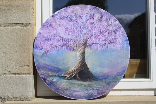 A purple tree against a blue background painted on a circular canvas, rested on a windowsill 