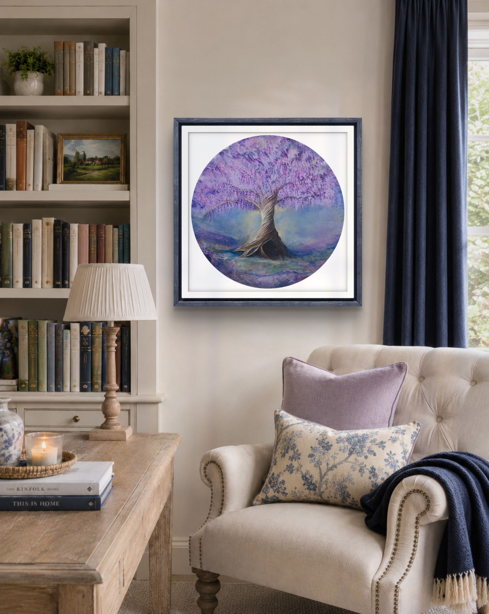 Living room with a framed artwork of a tree on a purple background, bookshelf, and armchair.